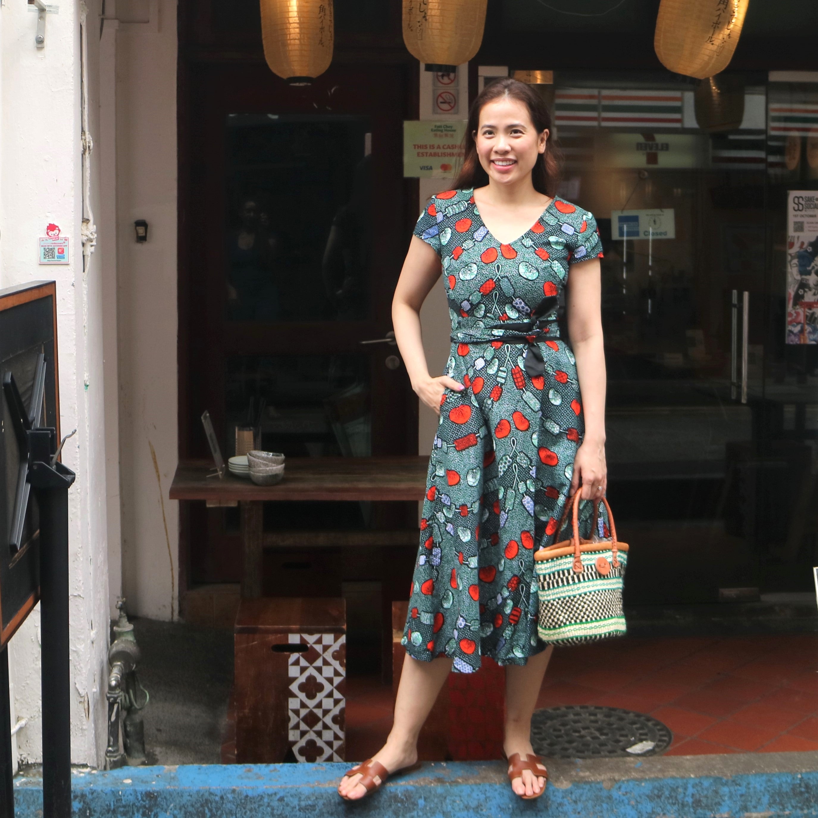Woman in a patterned dress standing in front of a store entrance.